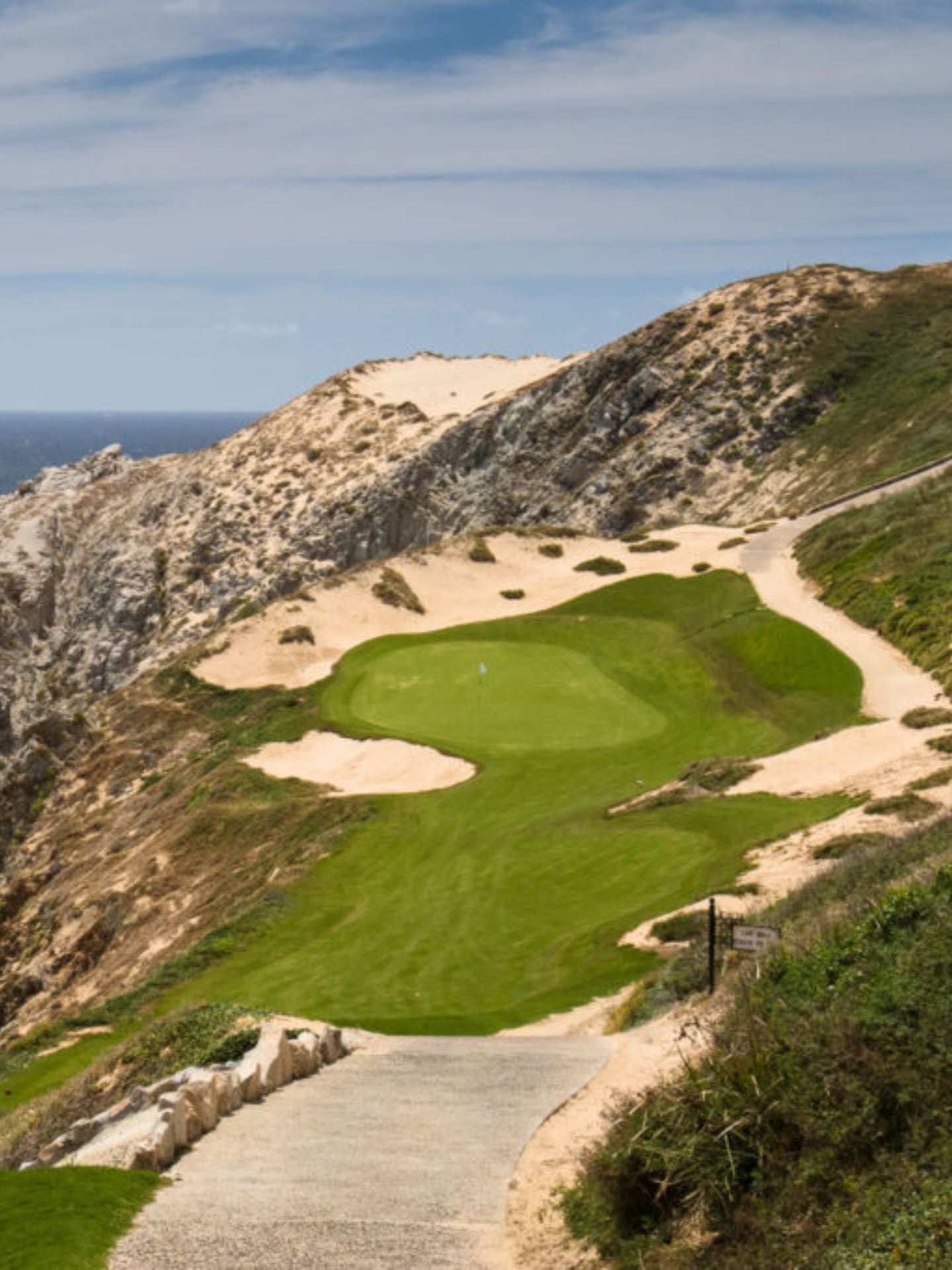 Beautiful view of a golf course built into a mountainside, overlooking the ocean.